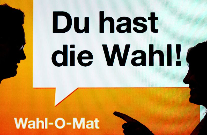 ARCHIV - ILLUSTRATION - Zwei junge Leute stehen am 22.08.2013 in München (Bayern) vor einen Bildschirm mit der Aufschrift «Du hast die Wahl! - Wahl-O-Mat». (Zu dpa "Musik, Wahl-«Tinder», Navi: Das sind die Apps zur Bundestagswahl" vom 29.08.2017) (© Foto: dpa)